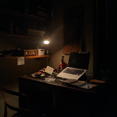 dimly lit room with table light and computer