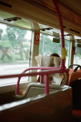 elderly woman reading newspaper on bus